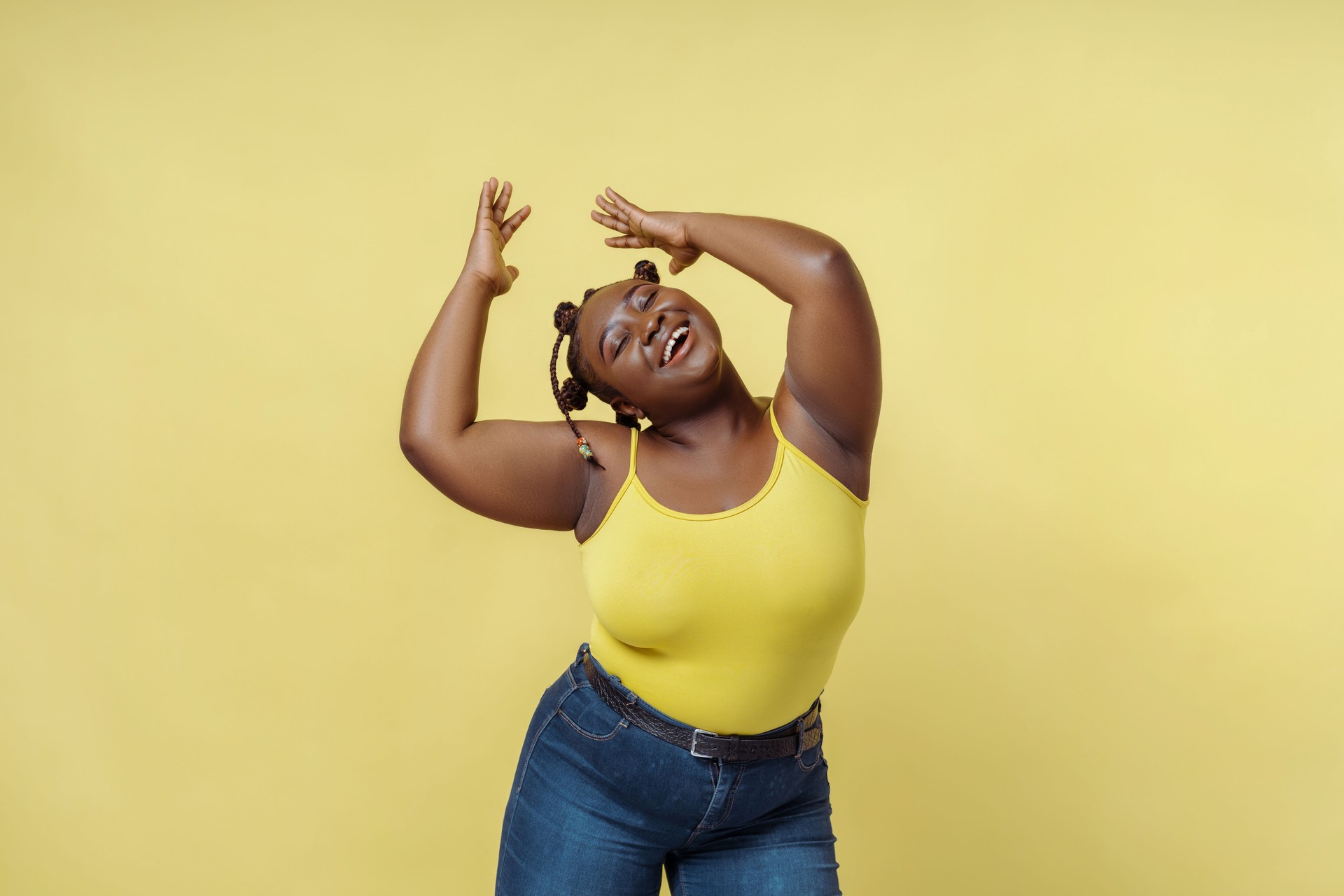 Smiling African American woman dancing isolated on yellow background. Beauty, body positive concept